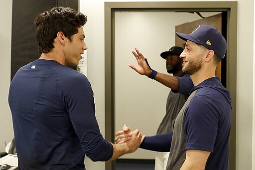 Milwaukee Brewers' Christian Yelich, left, greets teammate Ryan Braun after the Brewers announced Yelich's multi-year contract extension at the teams' spring training facility Friday, March 6, 2020, in Phoenix. (AP Photo/Matt York)