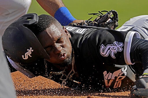 Chicago White Sox's Luis Robert is tagged by Texas Rangers third baseman Todd Frazier after sliding back to third on a double play hit into by Chicago White Sox's Adam Engel during the second inning of a spring training baseball game Saturday, Feb. 29, 2020, in Surprise, Ariz. Robert was ruled out at home on the play. (AP Photo/Charlie Riedel)