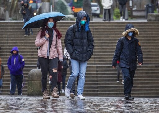 Students walking onto the University of Washington Friday, March 6, 2020, after it was announced starting Monday, March 9 in-person classes were cancelled due to coronavirus concerns. (Steve Ringman/The Seattle Times via AP)