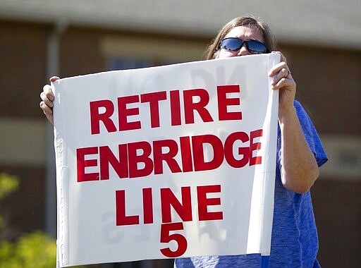 FILE - In this Thursday, July 6, 2017, file photo, Lauren Sargent, of Ann Arbor, Mich., takes part in a protest before the Enbridge Line 5 pipeline public information session at Holt High School in Holt, Mich. Enbridge Inc. said Friday, March 6, 2020, it has hired companies to design and build a disputed oil pipeline tunnel beneath the channel linking Lakes Huron and Michigan, despite pending legal challenges. (Cory Morse/The Grand Rapids Press via AP, File)