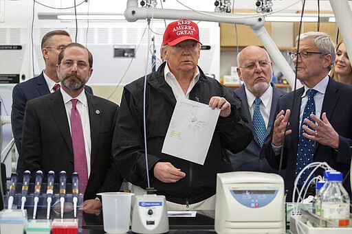 President Donald Trump holds up a picture as he listens during a meeting with Health and Human Services Secretary Alex Azar, left, Associate Director for Laboratory Science and Safety Steve Monroe, and Centers for Disease Control and Prevention Director Dr. Robert Redfield, about the coronavirus at the Centers for Disease Control and Prevention, Friday, March 6, 2020 in Atlanta. (AP Photo/Alex Brandon)