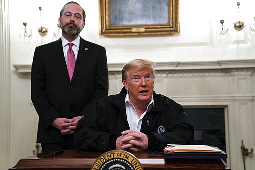 Secretary of Health and Human Services Alex Azar listens as President Donald Trump talks to reporters during a signing of a spending bill to combat the coronavirus, at the White House, Friday, March 6, 2020, in Washington. (AP Photo/Evan Vucci)