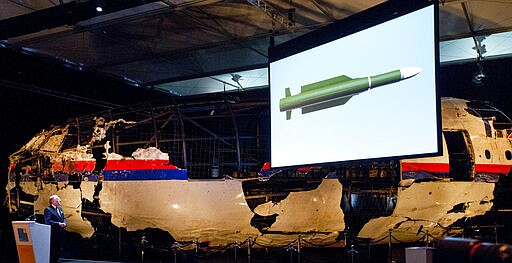 -FILE- In this Tuesday, Oct. 13, 2015, file image, a video shows a missile while a part of the reconstructed forward section of the fuselage is displayed behind, as Tjibbe Joustra, left, head of the Dutch Safety Board presents the board's final report into what caused Malaysia Airlines Flight 17 to break up high over Eastern Ukraine last year, killing all 298 people on board, during a press conference in Gilze-Rijen, central Netherlands, Tuesday, Oct. 13, 2015. United by grief across oceans and continents, families who lost loved ones when Malaysia Airlines Flight 17 was shot down in 2014 hope that a trial starting next week will finally deliver them something that has remained elusive ever since: The truth. (AP Photo/Peter Dejong, File)