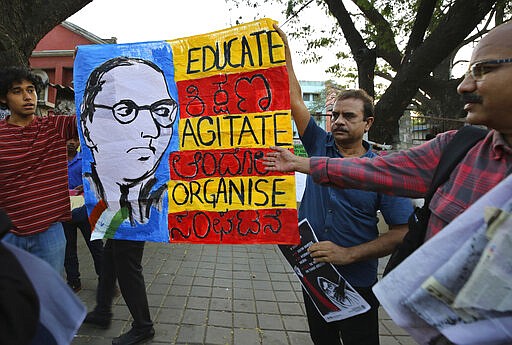 In this Tuesday, Feb. 4, 2020 photo, Indians hold a banner featuring sketch of Bhim Rao Ambedkar, the freedom fighter who is also regarded as the architect of Indian constitution, during a protest against the sedition case filed by police against a school after a play preformed by students denouncing a new citizenship law, in Bangalore, India. Critics, intellectuals, human rights activists, filmmakers, students and journalists in seen as opposed to Indian Prime Minister Narendra Modi's government are being increasingly silenced under a colonial-era sedition law. Official data reveal as many as 332 people were arrested under the law between 2016 and 2018, though only seven were convicted, suggesting that the police have struggled to gather evidence against the accused. (AP Photo/Aijaz Rahi)