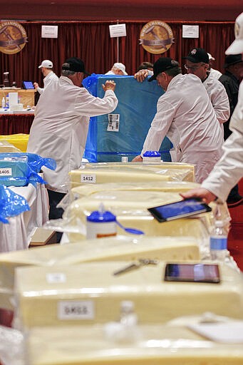 World Championship Cheese Contest committee members Gary Grossen, left, Gordy Bergemann, right, and Dan Stearns, rear, turn a block of Swiss cheese at the biennial World Championship Cheese Contest, Tuesday, March 3, 2020, at the Monona Terrace Convention Center in Madison, Wis. It's the largest technical cheese, butter and yogurt competition in the world. This year the competition had a record 3,667 entries from 26 nations. (AP Photo/Carrie Antlfinger)