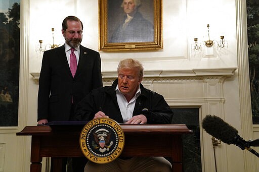 President Donald Trump signs an $8.3 billion bill to fight the coronavirus outbreak in the U.S., Friday, March 6, 2020 at the White House in Washington, as Department of Health and Human Services Secretary Alex Azar, looks on.  The legislation provides federal public health agencies with money for vaccines, tests and potential treatments and helps state and local governments prepare and respond to the threat. The rapid spread of the virus has rocked financial markets, interrupted travel and threatens to affect everyday life in the United States.   (AP Photo/Evan Vucci)