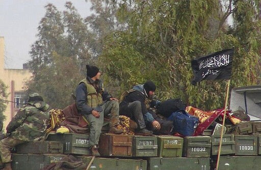 FILE - In this Friday, Jan. 11, 2013 file photo, provided by an anti-Bashar Assad activist group Edlib News Network (ENN), which has been authenticated based on its contents and other AP reporting, rebels from al-Qaida-affiliated Nusra Front, sit on a truck full of ammunition at Taftanaz air base, that was captured by the rebels in Idlib province, northern Syria.Intermingled among 3 million civilians under siege in the Syrian government's assault on the last opposition stronghold are tens of thousands of al-Qaida-linked fighters and other militants who came from around the world to take part in the country's civil war. (Edlib News Network ENN via AP, File)