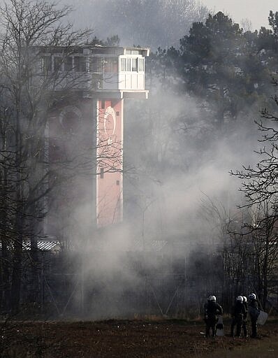 Greek riot police police is seen in front of a Turkish guard during clashes at the Greek-Turkish border in Kastanies, Evros region, on Friday, March 6, 2020. Thousands of refugees and other asylum-seekers have tried to enter Greece from the land and sea in the week since Turkey declared its previously guarded gateways to Europe open. (AP Photo/Giannis Papanikos)