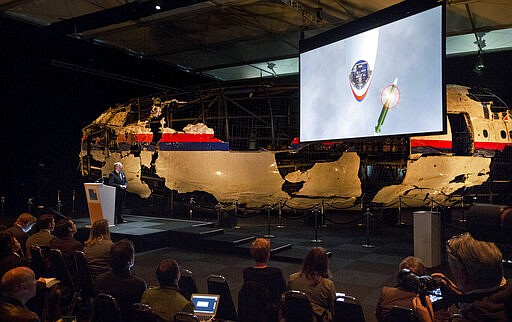 -FILE- In this Tuesday, Oct. 13, 2015, file image, a video shows the impact of a missile on Malaysia Airline Flight 17, while a part of the reconstructed forward section of the fuselage is displayed behind, as Tjibbe Joustra, left, head of the Dutch Safety Board presents the board's final report into what caused Malaysia Airlines Flight 17 to break up high over Eastern Ukraine last year, killing all 298 people on board, during a press conference in Gilze-Rijen, central Netherlands. United by grief across oceans and continents, families who lost loved ones when Malaysia Airlines Flight 17 was shot down in 2014 hope that a trial starting next week will finally deliver them something that has remained elusive ever since: The truth. (AP Photo/Peter Dejong, File)