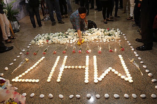 FILE - In this Friday, July 25, 2014 file photo, a Malaysia Airlines crew member places a flower next to candles forming the letters MH17 after a multi-faith prayers for the victims of the downed Malaysia Airlines Flight 17 at Malaysia Airlines Academy in Kelana Jaya, near Kuala Lumpur, Malaysia. United by grief across oceans and continents, families who lost loved ones when Malaysia Airlines Flight 17 was shot down in 2014 hope that a trial starting next week will finally deliver them something that has remained elusive ever since: The truth. (AP Photo/Lai Seng Sin, File)