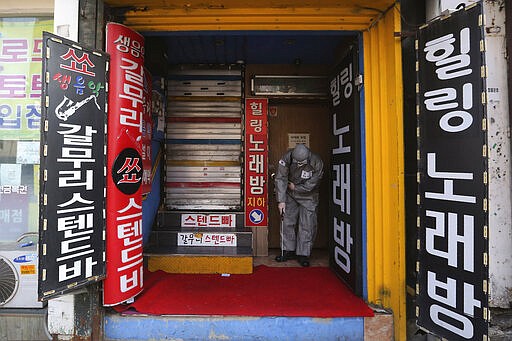 A South Korean army soldier sprays disinfectant as a precaution against the coronavirus in front of a Karaoke bar in Seoul, South Korea, Friday, March 6, 2020. North Korea said Friday it has released about 220 foreigners from a quarantine imposed as part of its vigilant prevention efforts to avoid an outbreak of the coronavirus that has spread around the world.(AP Photo/Ahn Young-joon)