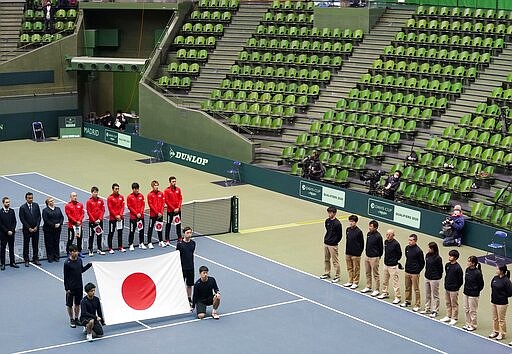 Japanese tennis players, in red uniform, attend the opening ceremony of the Davis Cup qualifier between Japan and Ecuador, as it is held without spectators amid growing concern about the spread of a new coronavirus in Miki city, Hyogo prefecture, western Japan, Friday, March 6, 2020. (Nobuki Ito/Kyodo News via AP, File)