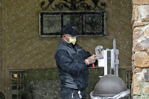 A worker adds hand sanitizer to a hygiene station, Friday, March 6, 2020, at the Life Care Center in Kirkland, Wash., which has become the epicenter of the COVID-19 coronavirus outbreak in Washington state. (AP Photo/Ted S. Warren)