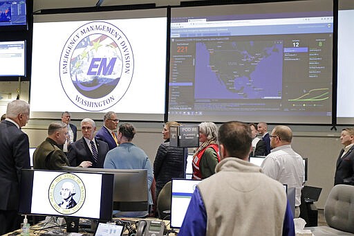 A map showing the spread of the COVID-19 coronavirus in the United States is displayed as Vice President Mike Pence, at lower left, tours the Washington State Emergency Operations Center, Thursday, March 5, 2020 at Camp Murray in Washington state. (AP Photo/Ted S. Warren)