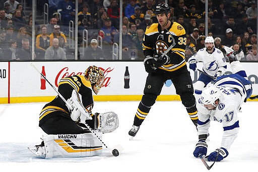 Boston Bruins goaltender Tuukka Rask, left, makes a save as defenseman Zdeno Chara (33) trips Tampa Bay Lightning's Alex Killorn during the first period of an NHL hockey game Saturday, March 7, 2020, in Boston. (AP Photo/Winslow Townson)