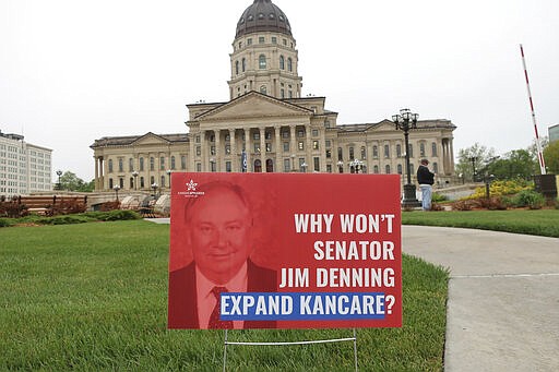 In this May 1, 2019 file photo a sign criticizing Kansas Senate majority leader Jim Denning, R-Overland Park and favoring Medicaid expansion was left on the Kansas Statehouse grounds after a protest in Topeka, Kan. Denning helped block a Medicaid expansion plan in 2019 but is now pushing a bipartisan plan he and Democratic Gov. Laura Kelly authored. (AP Photo/John Hanna)