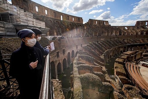 Tourists visit the Colosseum, in Rome, Saturday, March 7, 2020. With the coronavirus emergency deepening in Europe, Italy, a focal point in the contagion, risks falling back into recession as foreign tourists are spooked from visiting its cultural treasures and the global market shrinks for prized artisanal products, from fashion to design. (AP Photo/Andrew Medichini)