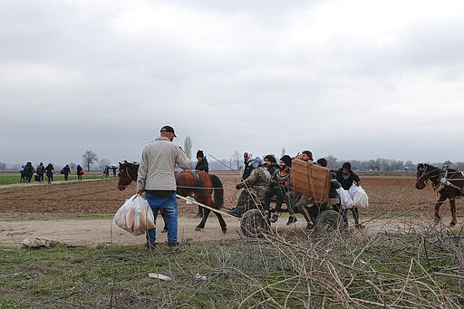 Migrants ride in a horse pulled cart near Pazarkule at the Turkish-Greek border on Thursday, March 5, 2020. Turkey has vowed to seek justice for a migrant it says was killed on the border with Greece after Greek authorities fired tear gas and stun grenades to push back dozens of people attempting to cross over. Greece had denied that anyone was killed in the clashes. (AP Photo/Darko Bandic)