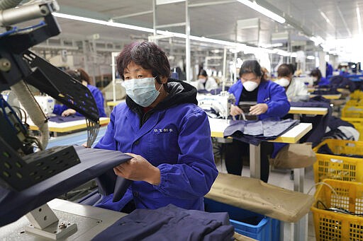 In this March 4, 2020 photo released by Xinhua News Agency, workers labor in a garment workshop while wearing masks at a foreign trade company in Neiqiu County of Xingtai City, north China's Hebei Province. China's exports fell by double digits in January and February as anti-virus controls closed factories, while imports sank by a smaller margin. (Zhu Xudong/Xinhua via AP)