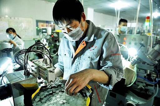 FILE - In this Feb. 23, 2020, file photo, workers make optical lenses in a factory in Dexing city in central China's Jiangxi province. China&#146;s exports fell by double digits in January and February as anti-virus controls closed factories, while imports sank by a smaller margin. (Chinatopix Via AP, File)