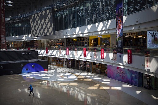 A deliveryman carries a food order as he walks through a mostly empty shopping mall in Beijing, Saturday, March 7, 2020. China's exports fell by double digits in January and February as anti-virus controls closed factories, while imports sank by a smaller margin. (AP Photo/Mark Schiefelbein)