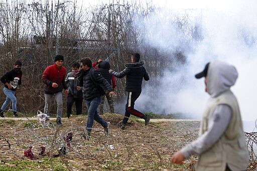 Migrants gather at a border fence on the Turkish side during clashes with the Greek riot police at the Turkish-Greek border in Pazarkule, Edirne region, on Saturday, March 7, 2020. Thousands of refugees and other migrants have been trying to get into EU member Greece in the past week after Turkey declared that its previously guarded borders with Europe were open. (AP Photo/Darko Bandic)