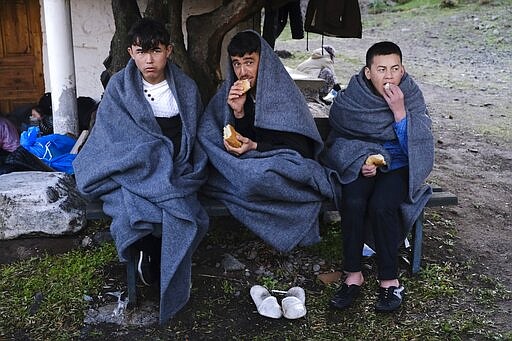 Migrants who arrived yesterday to Greece from Turkey eat bread as they try to warm themselves at the village of Skala Sikaminias, on the Greek island of Lesbos on Friday, March 6, 2020. Thousands of refugees and other asylum-seekers have tried to enter Greece from the land and sea in the week since Turkey declared its previously guarded gateways to Europe open. (AP Photo/Alexandros Michailidis)