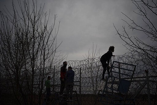 A migrant climbs a fence during clashes with the Greek riot police at the Turkish-Greek border in Pazarkule, Edirne region, Turkey, Friday, March 6, 2020. Clashes erupted anew on the Greek-Turkish border Friday as migrants attempted to push through into Greece, while the European Union's foreign ministers held an emergency meeting to discuss the situation on the border and in Syria, where Turkish troops are fighting. (AP Photo/Felipe Dana)