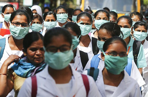 FILE - In this March 6, 2020, file photo, Indian nursing students wearing masks walk in a group at government run Gandhi Hospital in Hyderabad, India. As cases of the coronavirus surge in Italy, Iran, South Korea, the U.S. and elsewhere, many scientists say it's plain that the world is in the grips of a pandemic &#151; a serious global outbreak.  (AP Photo/Mahesh Kumar A.)