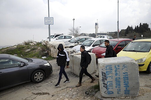 This Monday, Feb. 24 2020 photo, shows Palestinian students passing a roadblock at the entrance to the Palestinian neighborhood of Issawiya in East Jerusalem. Nearly every day for the last nine months Israeli police have stormed into Issawiya in a campaign they say is needed to maintain law and order. Rights groups say that in addition to searching houses and issuing fines, they have detained hundreds of people &#151; some as young as 10, on suspicion of stone-throwing. The operations frequently ignite clashes, with local youths throwing rocks and firebombs. Residents and human rights groups say the provocative raids have created an atmosphere of terror, with parents afraid to let their children play outside. (AP Photo/Mahmoud Illean)