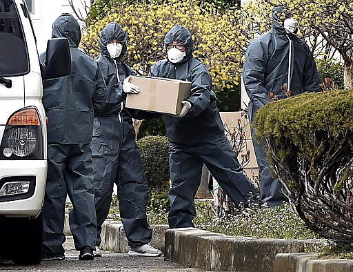 Health officials carry daily necessities into an apartment in Daegu, South Korea, Saturday, March 7, 2020. The apartment complex has been put under group isolation after a mass infection was reported amid the rise in confirmed COVID-19 disease. (Lee Moo-ryul/Yonhap via AP)