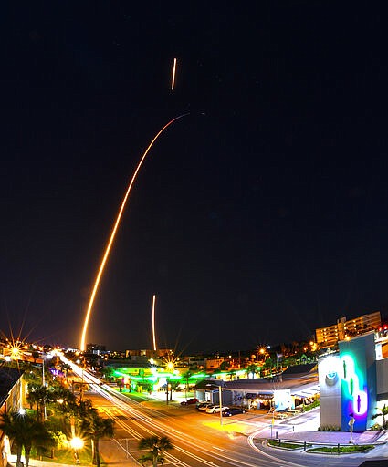 In a time exposure from Cocoa Beach, Fla., a SpaceX Falcon rocket leaves a long trail after launch Friday, March 6, 2020, from Cape Canaveral, Fla. The two shorter streaks are from the first-stage booster firing on its return for a landing at Cape Canaveral. (Malcolm Denemark/Florida Today via AP)