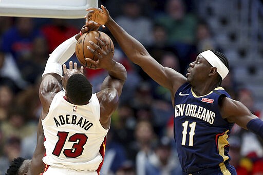 New Orleans Pelicans guard Jrue Holiday (11) knocks the ball from the grasp of Miami Heat forward Bam Adebayo (13) during the second half of an NBA basketball game in New Orleans, Friday, March 6, 2020. (AP Photo/Rusty Costanza)