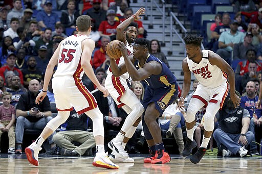 New Orleans Pelicans forward Zion Williamson (1) fights through traffic as Miami Heat forwards Derrick Jones Jr. and Jimmy Butler (22) defend during the first half of an NBA basketball game in New Orleans, Friday, March 6, 2020. (AP Photo/Rusty Costanza)