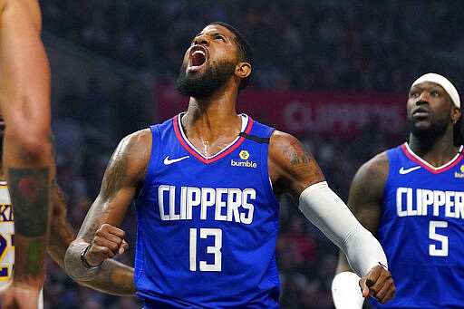 Los Angeles guard Paul George, left, yells as he scores while forward Montrezl Harrell watches during the first half of an NBA basketball game against the Los Angeles Lakers Sunday, March 8, 2020, in Los Angeles. (AP Photo/Mark J. Terrill)