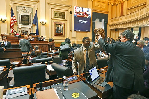 Del. Alfonzo Lopez, D-Arlington, right, and Del. Cliff Hayes, D-Chesapeake, give each other high fives with their baseball gloves after the House session at the Capitol Sunday March 8 , 2020, in Richmond, Va. (AP Photo/Steve Helber)