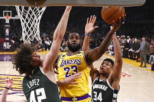 Los Angeles Lakers forward LeBron James, center, shoots as Milwaukee Bucks center Robin Lopez, left, and forward Giannis Antetokounmpo defend during the first half of an NBA basketball game Friday, March 6, 2020, in Los Angeles. (AP Photo/Mark J. Terrill)