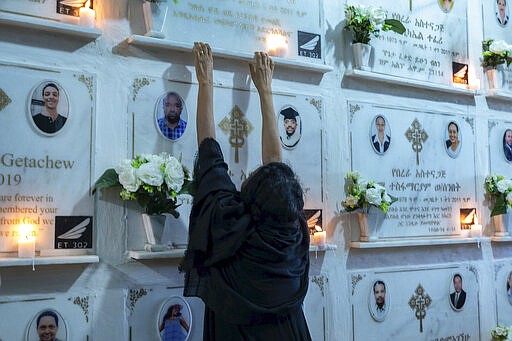 A relative reaches out as candles are lit on a memorial wall during an anniversary memorial service to remember those who died when Ethiopian Airlines flight ET302, a Boeing 737 Max, crashed shortly after takeoff on March 10, 2019 killing all 157 on board, at the Holy Trinity Cathedral in Addis Ababa, Ethiopia Sunday, March 8, 2020. (AP Photo/Mulugeta Ayene)