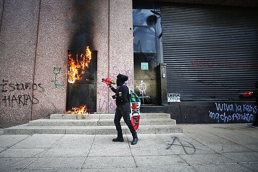 A demonstrator sets fire to the door of a building during a march for International Women's Day in Mexico City, Sunday, March 8, 2020. Protests against gender violence in Mexico have intensified in recent years amid an increase in killings of women and girls.(AP Photo/Rebecca Blackwell)