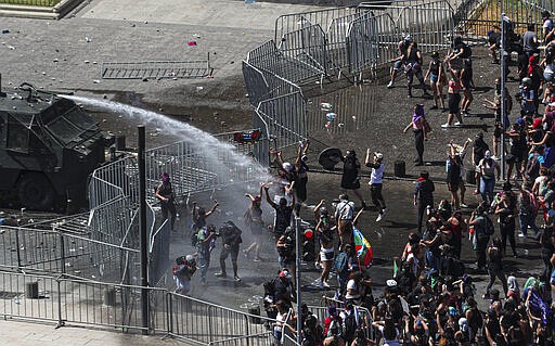 Women march and clash with police near La Moneda presidential palace during a protest marking International Women's Day, in Santiago, Chile, Sunday, March 8, 2020. (AP Photo/Esteban Felix)