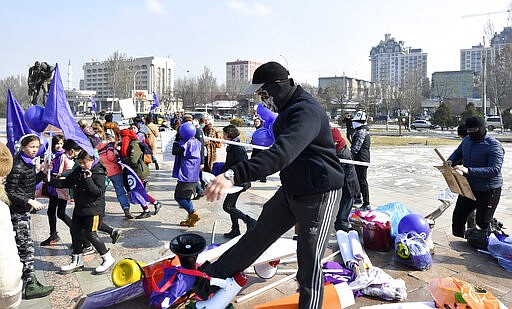 Masked Kyrgyz nationalists attack women's rights activists during the celebration of the International Women's Day at Victory Square in Bishkek, Kyrgyzstan, Sunday, March 8, 2020. (AP Photo/Vladimir Voronin)