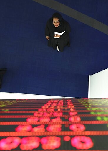 A woman checks the stocks on the screen at the Dubai Financial Market in Dubai, United Arab Emirates, Sunday, March 8, 2020. Stocks markets in the Mideast suffered sharp drops in early trading Sunday over fears about the new coronavirus and demand in crude oil falling amid a failure by OPEC and allied nations to cut production. (AP Photo/Kamran Jebreili)