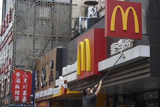 A worker cleans the signage of a fast food restaurant as businesses slowly restart in Beijing on Sunday, March 8, 2020. As China's coronavirus cases and death steadily falls, authorities are trying to restart its businesses and factories after a virtual shutdown which has had a ripple effect affecting the global economy. (AP Photo/Ng Han Guan)