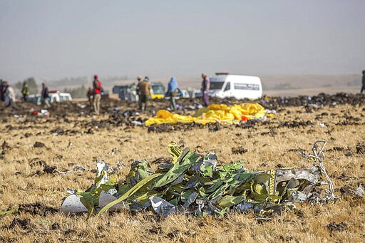 FILE - In this March 11, 2019 file photo, parts of the plane wreckage lie at the scene where the Ethiopian Airlines Boeing 737 Max 8 crashed shortly after takeoff on Sunday killing all 157 on board at the crash site at Bishoftu, or Debre Zeit, outside Addis Ababa, Ethiopia. When air safety investigators release an interim report on the crash of an Ethiopian Airlines Boeing 737 Max sometime before Tuesday, March 10, 2020, the one-year anniversary of the crash, they are likely to place the blame on the jet's automated flight control system as well as on the pilots and their training, but it's unclear yet which side will bear the brunt. (AP Photo/Mulugeta Ayene, File)