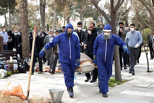 Men wearing protective gear carry the body of Fatemeh Rahbar, a lawmaker-elect from a Tehran constituency, who died on Saturday after being infected with the new coronavirus, at Behesht-e-Zahra cemetery, just outside Tehran, Iran, Sunday, March 8, 2020. Rahbar previously served three terms as lawmaker. With the approaching Persian New Year, known as Nowruz, officials kept up pressure on people not to travel and to stay home. Health Ministry spokesman Kianoush Jahanpour, who gave Iran's new casualty figures Sunday, reiterated that people should not even attend funerals. (Mehdi Khanlari/Fars News Agency via AP)