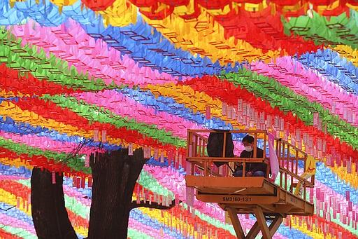 A worker wearing a face mask watches his smart phone under lanterns in preparation for the upcoming birthday of Buddha on April 30 at the Chogyesa temple in Seoul, South Korea, Sunday, March 8, 2020. The number of infections of the COVID-19 disease continues to spread around the globe. (AP Photo/Ahn Young-joon)