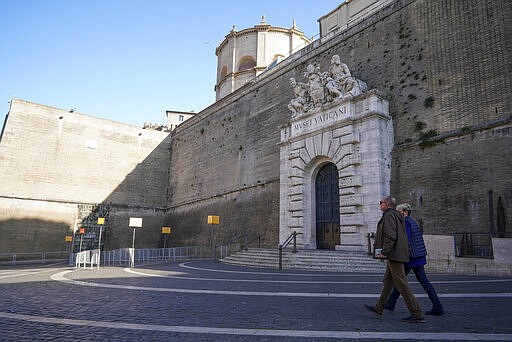 People walk outside the closed entrance of the Vatican Museums, at the Vatican, Sunday, March 8, 2020. The Vatican announced Sunday that in coordination with drastic Italian government measures aimed at containing Italy's virus outbreak, Europe's worst, it is shutting down its museums, which include access to the Sistine Chapel, until April 3.  (AP Photo/Andrew Medichini)