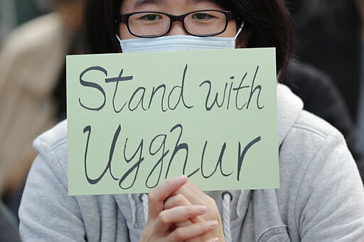 FILE - In this Dec. 22, 2019, file photo, a man holds a sign during a rally to show support for Uighurs and their fight for human rights in Hong Kong. People from western China who are targets of a Chinese government crackdown say they have been threatened and harassed in the United States. Those fleeing the crackdown on the predominantly Muslim Uighur ethnic group typically receive U.S. asylum. But Uighurs tell The Associated Press and human rights groups they still afraid amid threats aimed at them and their families back in China. (AP Photo/Lee Jin-man, File)