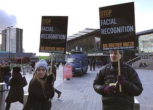 Rights campaigner Silkie Carlo, left, demonstrates in front of a mobile police facial recognition facility outside a shopping centre in London Tuesday Feb. 11, 2020, &#147;We don't accept this. This isn't what you do in a democracy,&quot; said Carlo, director of privacy campaign group Big Brother Watch. London police started using facial recognition surveillance cameras mounted on a blue police van on Tuesday to automatically scan for wanted people, as authorities adopt the controversial technology that has raised concerns about increased surveillance and erosion of privacy. (AP Photo/Kelvin Chan)