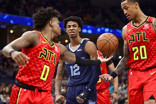 Memphis Grizzlies guard Ja Morant (12) reacts between Atlanta Hawks guard Brandon Goodwin (0) and forward John Collins (20) after scoring in the second half of an NBA basketball game Saturday, March 7, 2020, in Memphis, Tenn. (AP Photo/Brandon Dill)